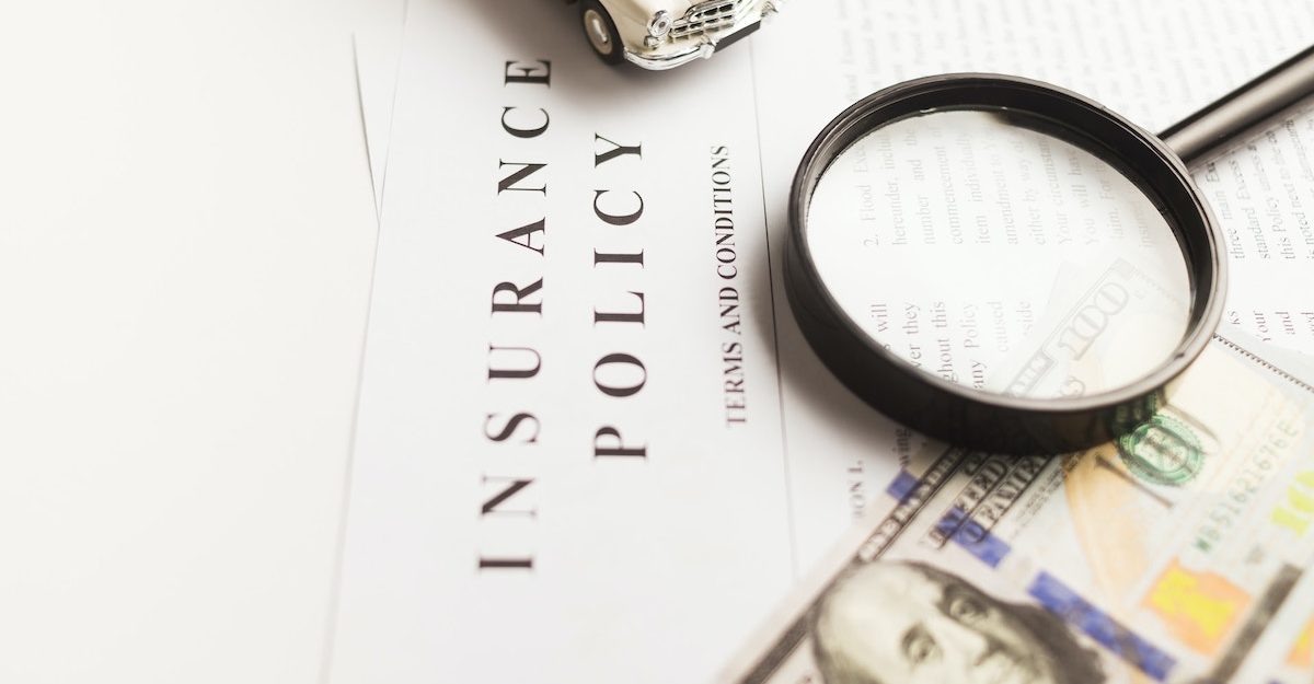 A magnifying glass, toy car and American money sit on top of a stack of papers titled 'Insurance Policy'. Insurance Bureau of Canada employees are entitled to severance when they lose their job.