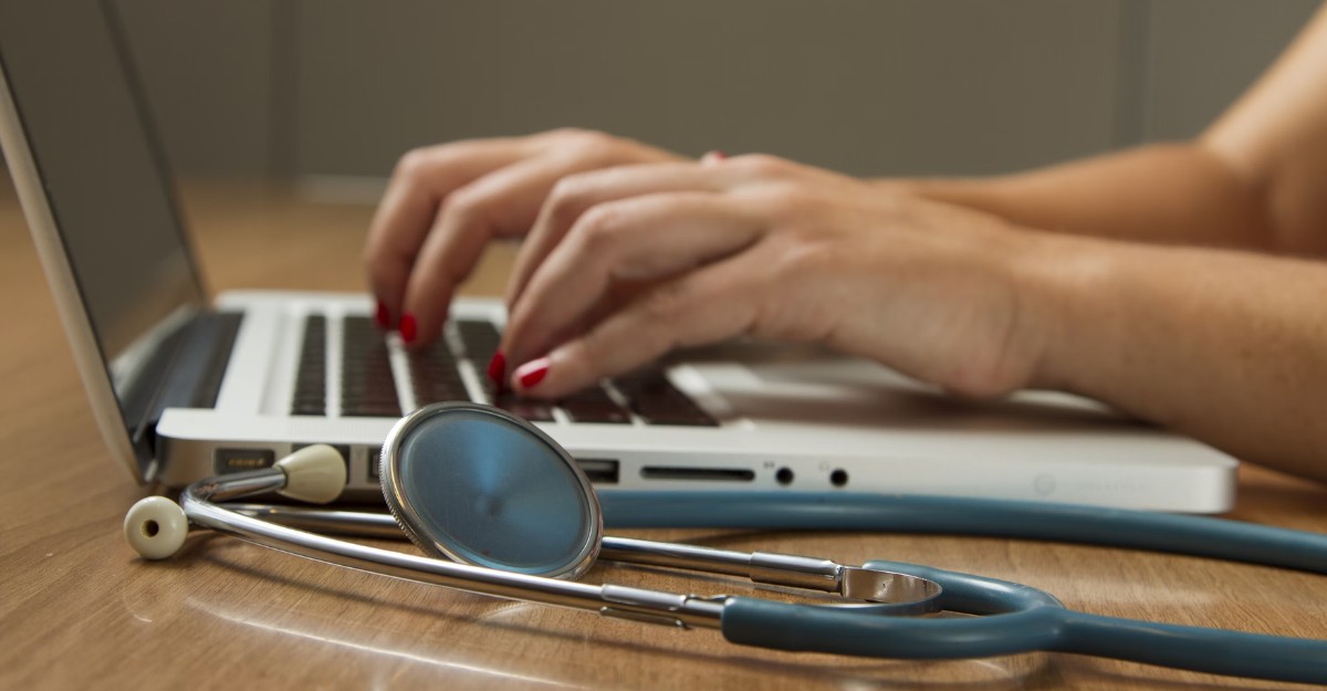 A person uses a laptop with a stethoscope beside them. (Photo: National Cancer Institute / Unsplash)