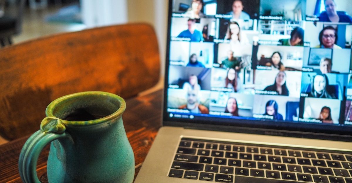 A videoconference featuring a dozen participants is shown on a laptop screen. Zoom employees are entitled to full severance pay when they lose their job.