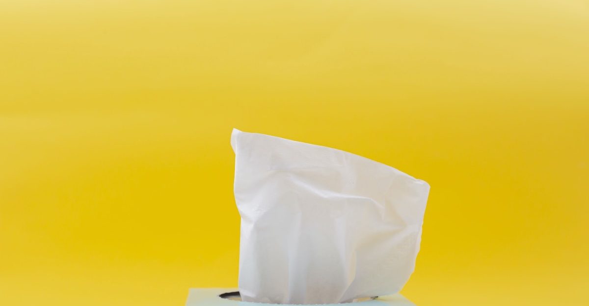 An image of a tissue sticking out of a box, set against a yellow background. Kimberly-Clark employees are entitled to severance when they lose their job.