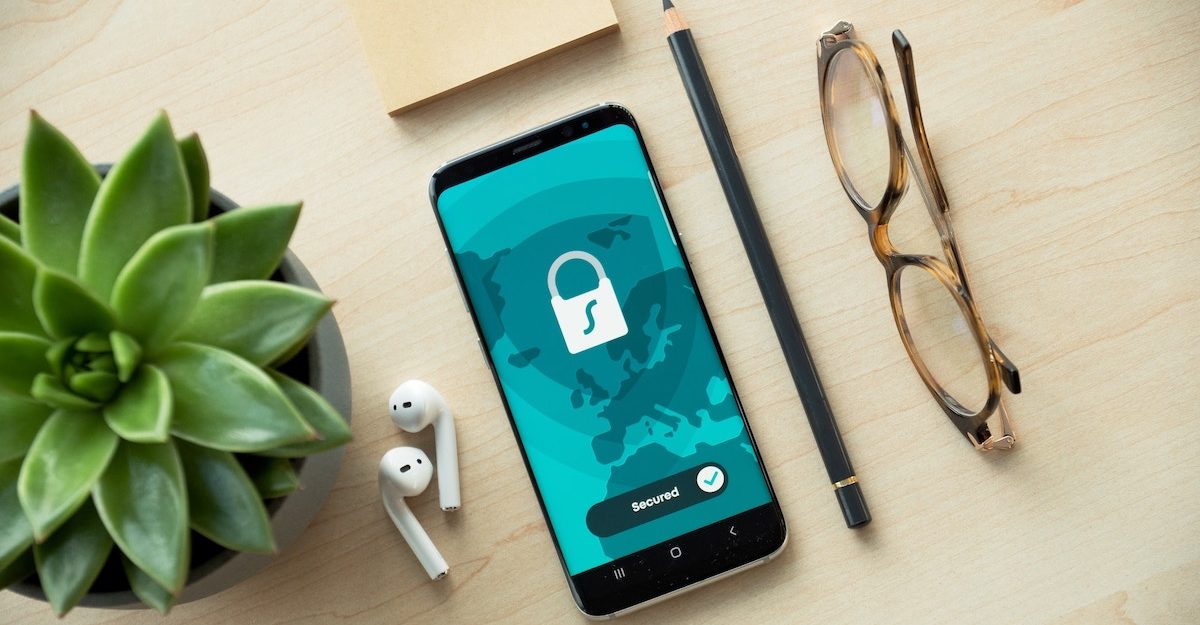 An iphone featuring a locked and secure screen lies on a table next to airpods, a pencil and glasses. SecureWorks employees are entitled to severance pay when they lose their job.