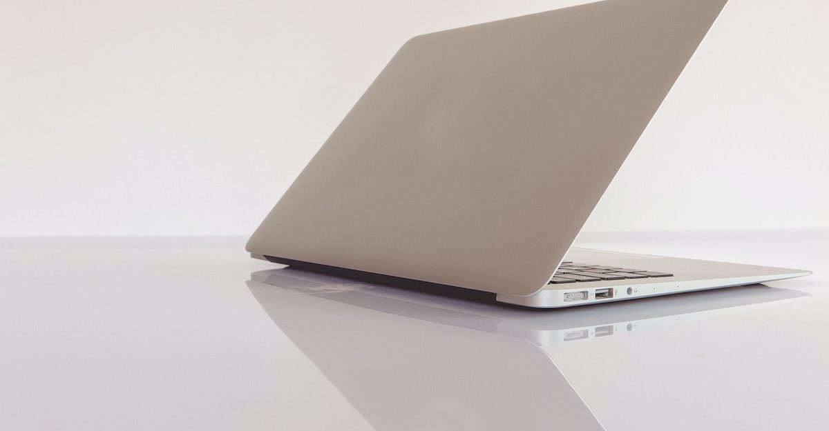 A grey laptop sits on a reflective glass table with the screen open slightly. Canada Computers employees are entitled to severance pay when they lose their job.
