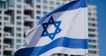 The Israeli flag is shown, held aloft by a strong breeze.