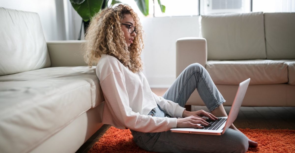 A photo of a person looking at a laptop while sitting on the floor. (Photo: Thought Catalog / Unsplash)