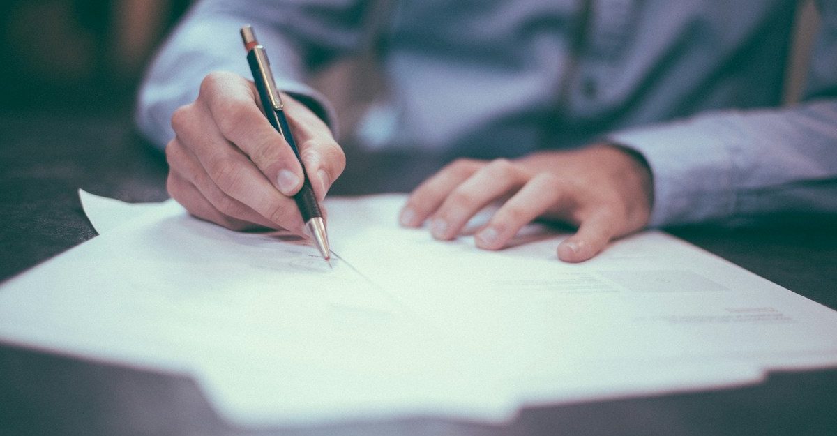 An individual signs insurance documents, like those provided by Zurich Canada.