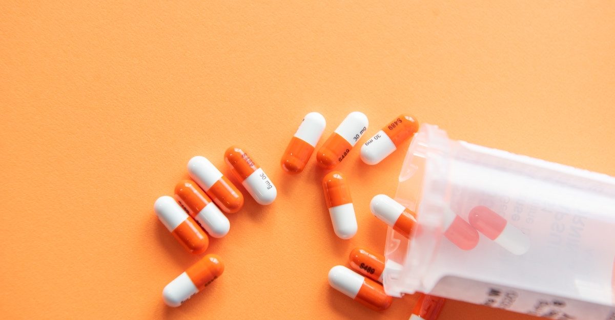 A photo of a dozen pills next to a pill bottle lying on its side, potentially a Bayer product.