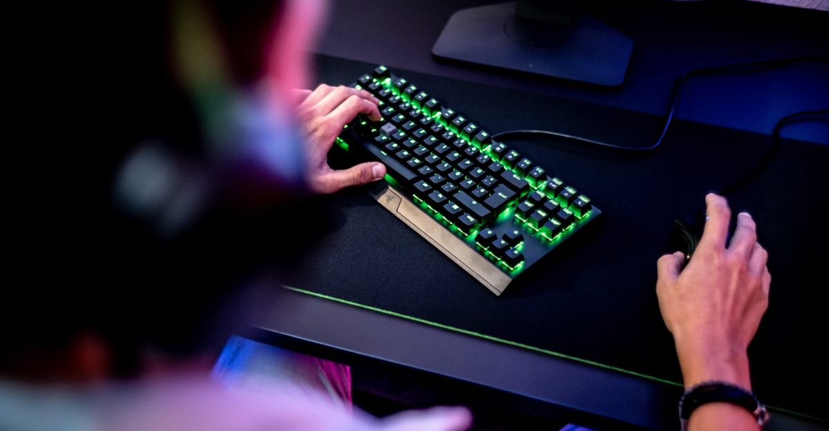 A photo of a person with headphones on using a mouse and keyboard. (Photo: ELLA DON / Unsplash)