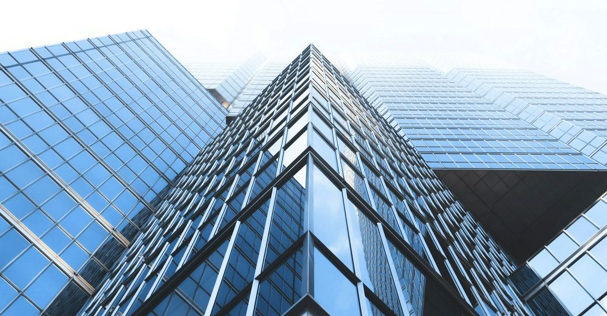 Looking up at a large building consisting of many panels of glass, potentially operated by Cogir.