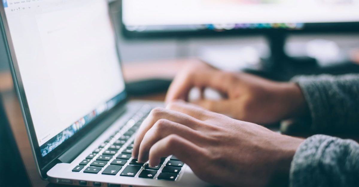 A close up of someone's hands hovering over a laptop keyboard, potentially working for HCL Canada.