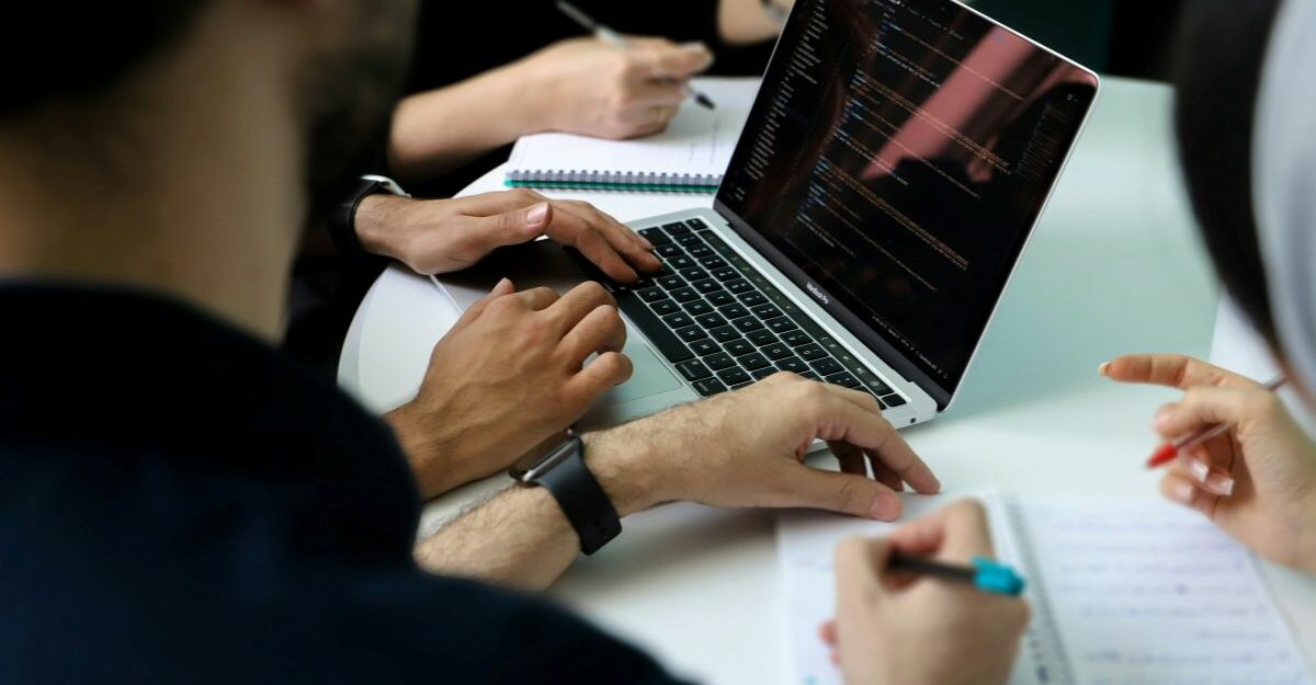A close-up of multiple hands hard at work during a strategy meeting.