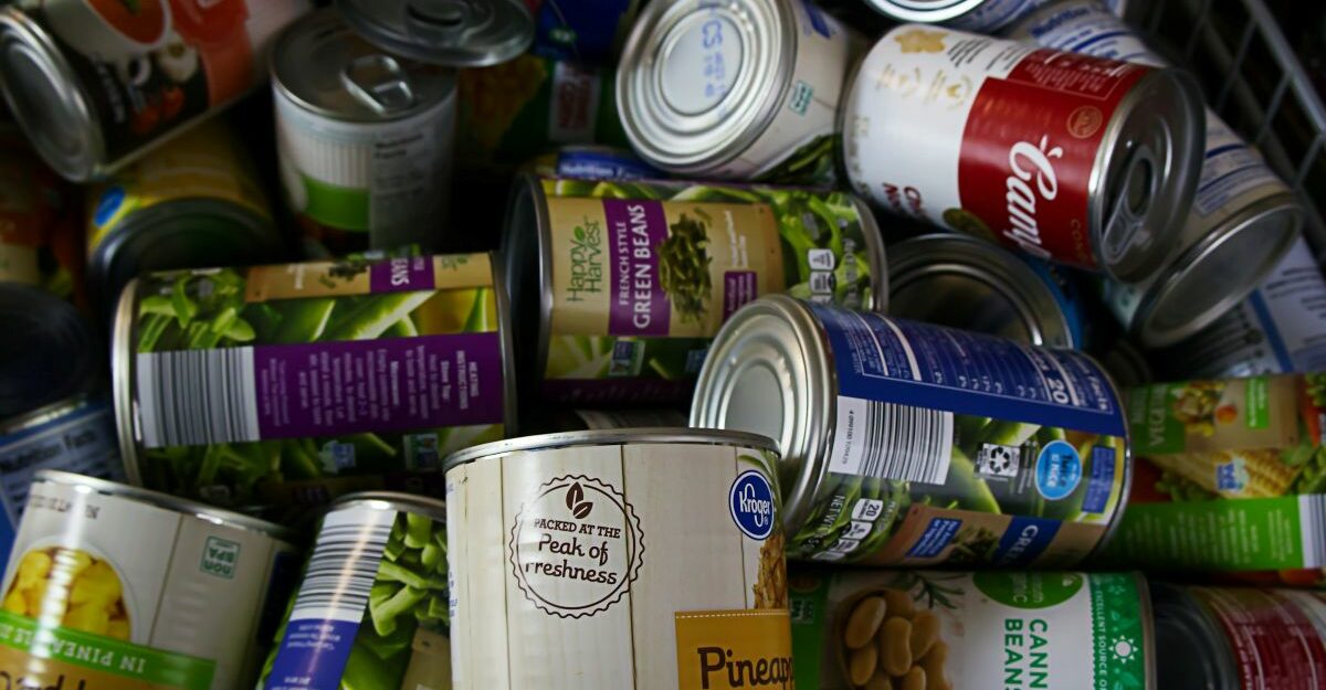 Numerous cans of food are seen piled on top of each other.