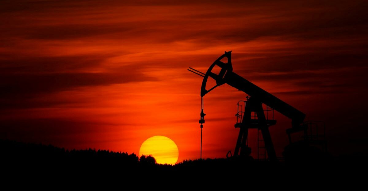 An oil pump set against a red sky illuminated by the setting sun.