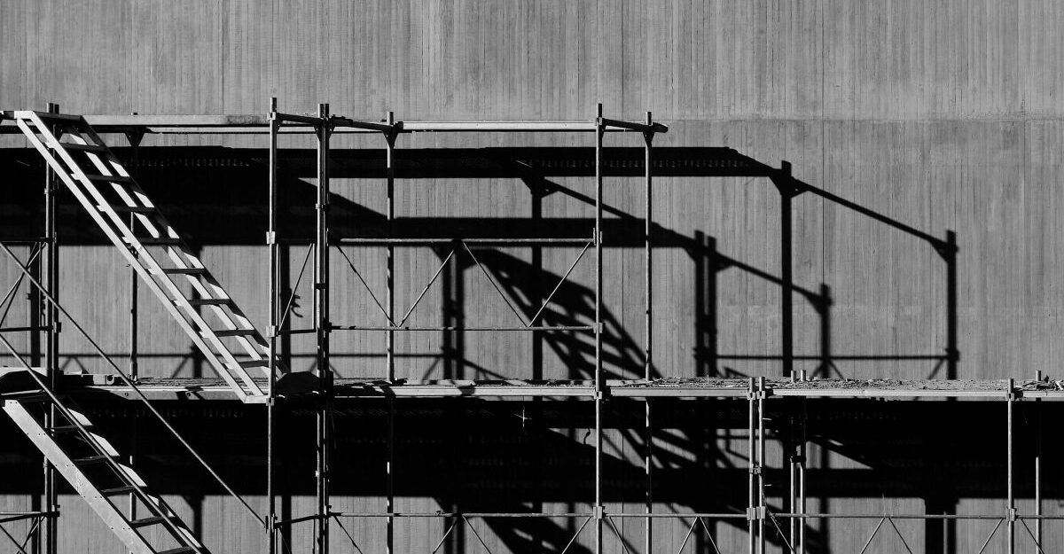 Metal scaffolding is setup against a large wall.