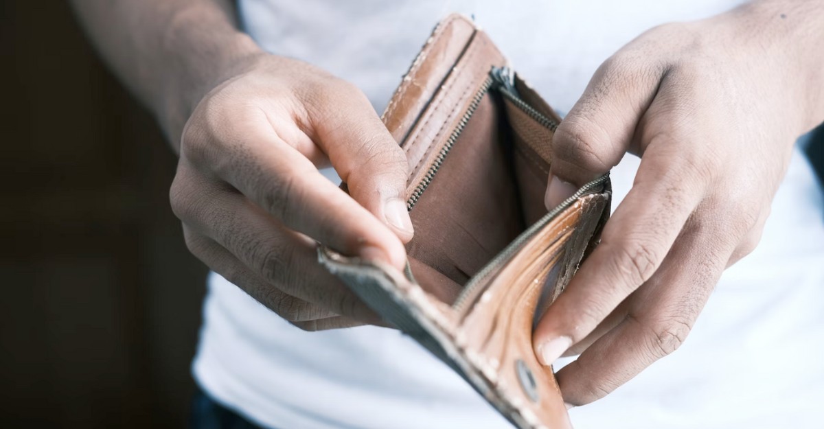 A man opens a brown leather wallet to reveal that it's empty. (Photo: Towfiqu Barbhuiya / Unsplash)