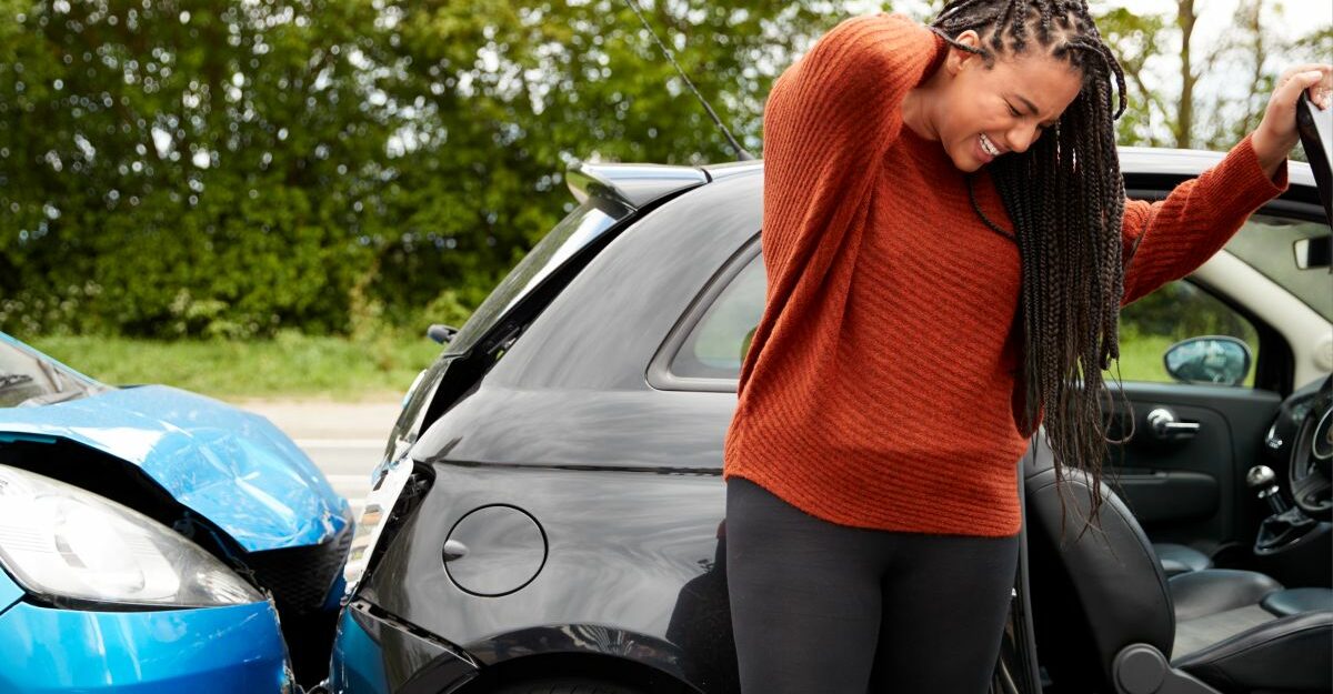 A woman rubs her neck after experiencing painful whiplash in a car accident.
