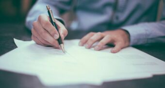 A person signing legal documents at a desk, illustrating deadlines and paperwork related to the statute of limitations in Ontario.