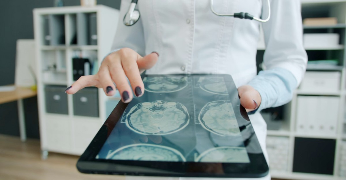 A doctor reviews brain scans on a digital tablet. (Photo: Vitaly Gariev / Unsplash)