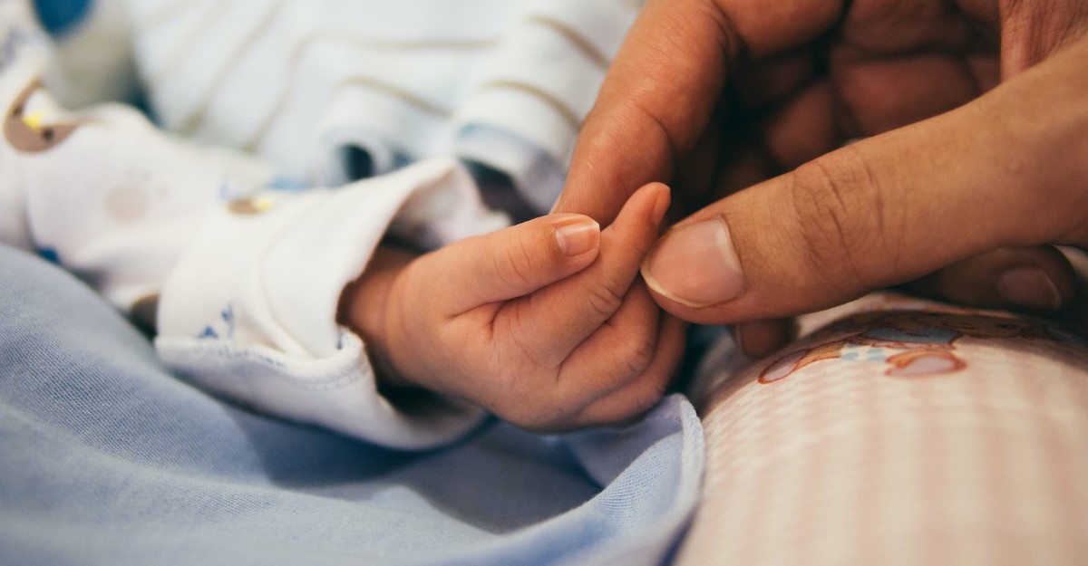 A mother holding her child's hand while on parental leave in Canada.