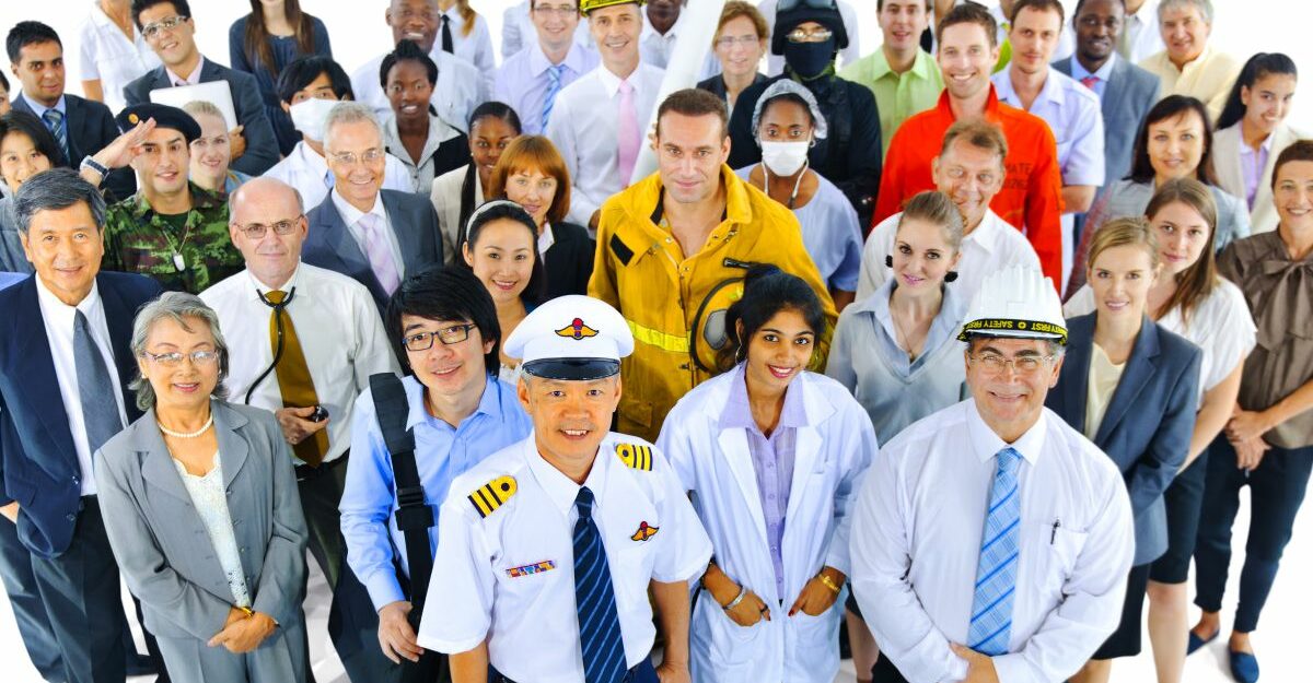 A diverse group of British Columbia workers from different professions, including healthcare, trades, aviation, and office roles, standing together and smiling.