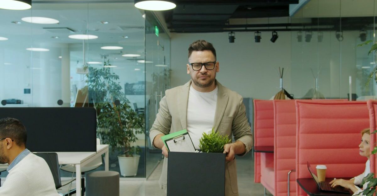 Employee carrying a box after a reduction in force (RIF) layoff in a modern office