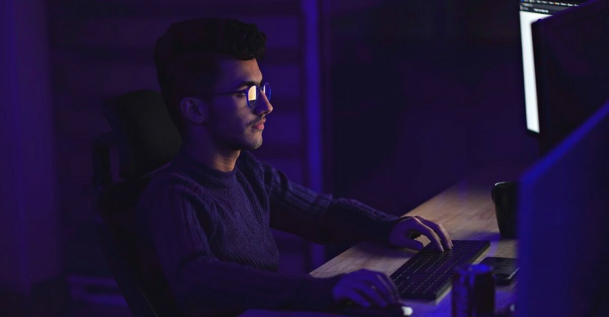 A person looking at multiple computer screens. (Photo: Mohammad Rahmani / Unsplash)