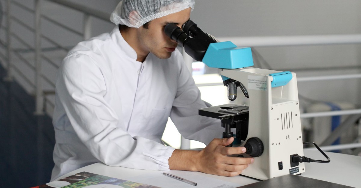 A scientist studies a slide under a microscope. (Photo: Lucas Vasques / Unsplash)