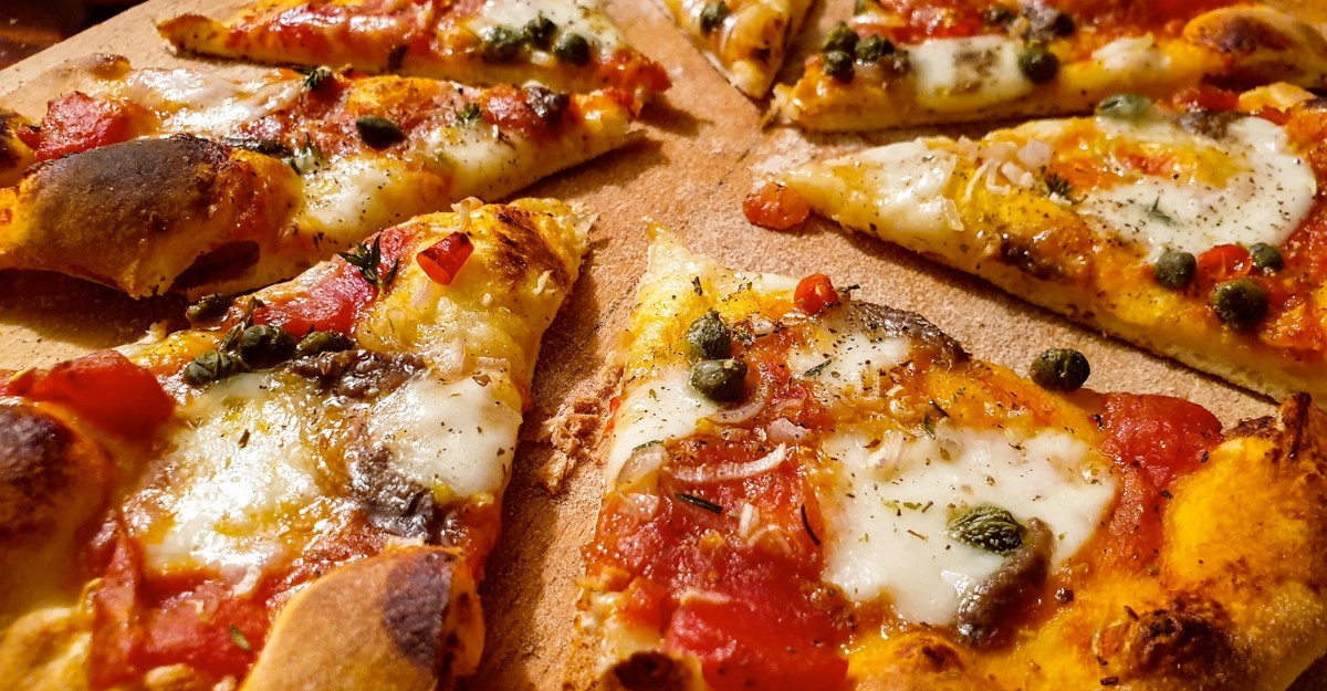 A loaded pizza sitting on a wooden pizza board. (Photo: Henry Perks / Unsplash)