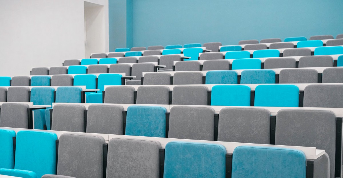 A lecture hall with blue and grey seats. (Photo: rutmiit / Unsplash)